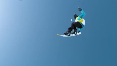 Erkek turist havada uçuyor ve snowboard hilesi yapıyor..