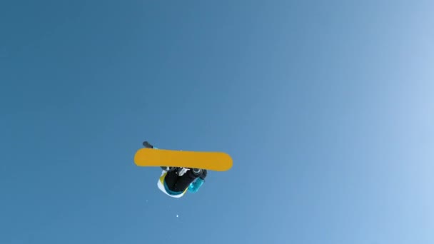 SLOW MOTION: Snowboarder pula fora do pontapé e faz um truque de garra rotativa. — Vídeo de Stock