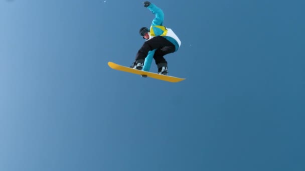 Movimiento lento: Joven snowboarder macho captura de aire grande y haciendo un truco de rotación. — Vídeo de stock