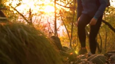 Çoraplı bir kadın güneşli bir sonbahar sabahında kayalık bir patikada yürüyüş yapar..
