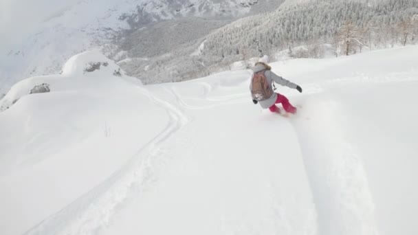 SLOW MOTION: Young woman carves fresh powder snow while snowboarding off piste. — Stockvideo
