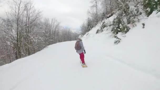 Onherkenbare vrouw snowboards langs de piste van het skigebied leidt door een bos. — Stockvideo
