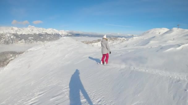 SLOW MOTION: Vrouwelijke snowboarder versnippert verse poedersneeuw tijdens het rijden off-piste. — Stockvideo