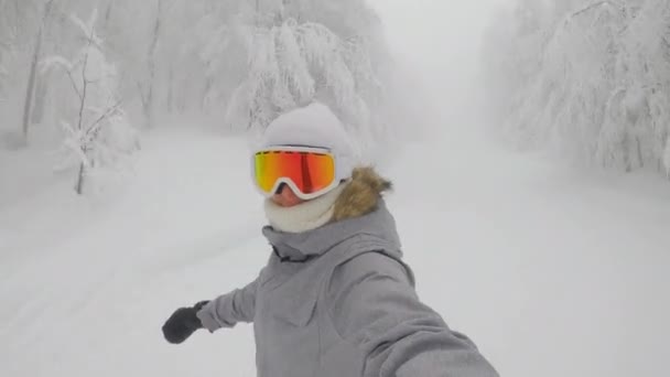 SELFIE: Female snowboarder with orange goggles rides along a ski resort slope. — Stock Video