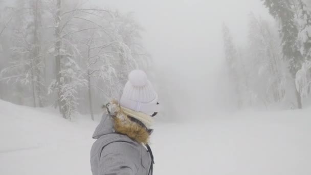 SELFIE : Femme snowboards le long d'une pente damée menant à travers la forêt brumeuse. — Video