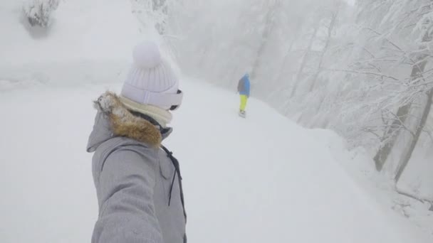 SELFIE Croisière des snowboarders le long d'une pente de station de ski traversant des bois brumeux. — Video