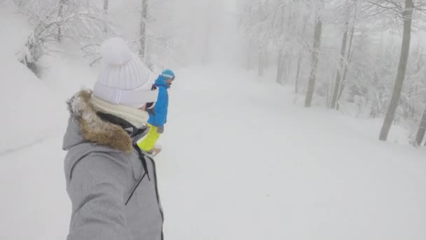 SELFIE: Giovani donne e uomini attivi stanno facendo snowboard lungo un percorso forestale nebbioso. — Video Stock