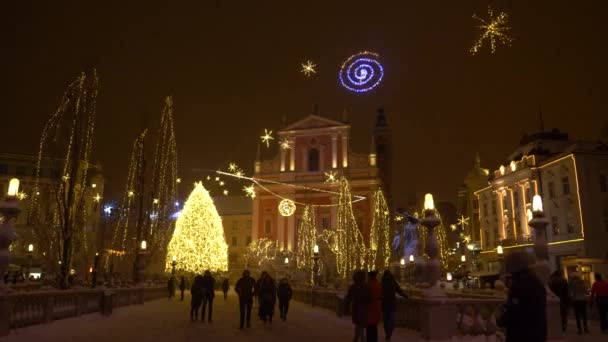 Tourists walk across a bridge and towards the Christmas tree in Preseren square. — 图库视频影像