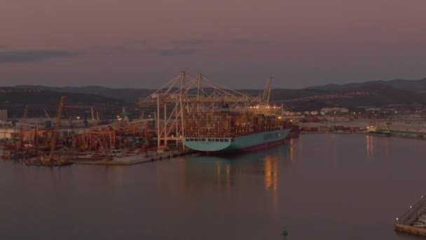 AERIAL: Flying towards a large freight ship in Koper getting unloaded at dawn. — 图库视频影像