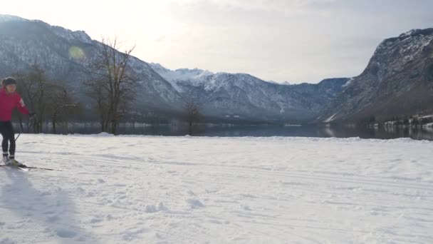 CERRAR: Mujer joven entrena esquí nórdico cerca del pintoresco lago Bohinj. — Vídeos de Stock