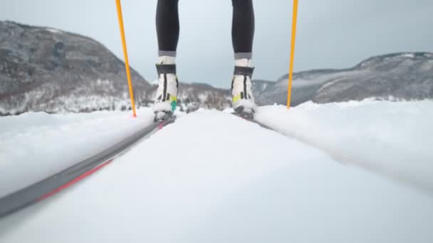 ÁNGULO BAJO: Esquís de atleta femenina a lo largo de pistas que corren alrededor de un centro de entrenamiento. — Vídeos de Stock