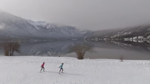 AERIAL: Vuelo a lo largo de dos atletas que entrenan esquí nórdico en montañas eslovenas. — Vídeo de stock