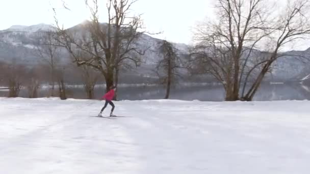 AERIAL: Nordic skiër treinen in de buurt van prachtige meer Bohinj op een zonnige winterochtend. — Stockvideo