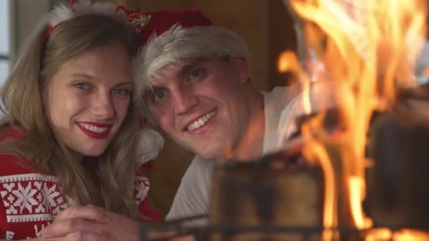 PORTRAIT, CLOSE UP: Усміхнена пара насолоджується різдвяними святами біля каміна — стокове відео
