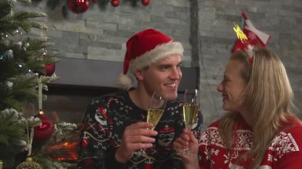 Κοντινό πλάνο: Εορταστικό νεαρό ζευγάρι στην πρόποση και πίνοντας σαμπάνια την παραμονή των Χριστουγέννων — Αρχείο Βίντεο