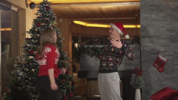 Fröhliches Paar tanzt zu fröhlicher Musik und feiert Weihnachten zu Hause — Stockvideo