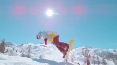 Snowboard 'cu bir profesyonelin dönen bir topu tutarken görüntüsü..