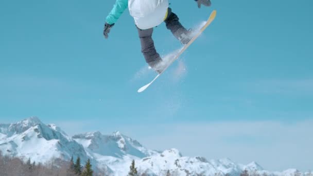 SLOW MOTION Mannelijke snowboarder vliegt door de lucht en doet een draaiende neus grijpen — Stockvideo