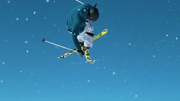 CLOSE UP: Skifahrer zieht einen Kicker aus und dreht sich mit gekreuzten Skiern. — Stockvideo