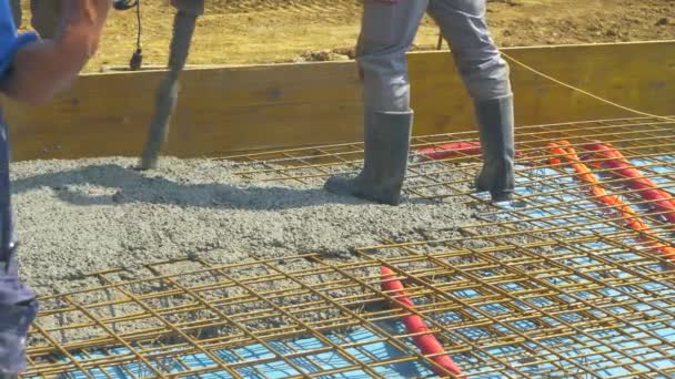 CERRAR: Los constructores vierten la mezcla de cemento húmedo sobre una capa de malla metálica. — Vídeo de stock