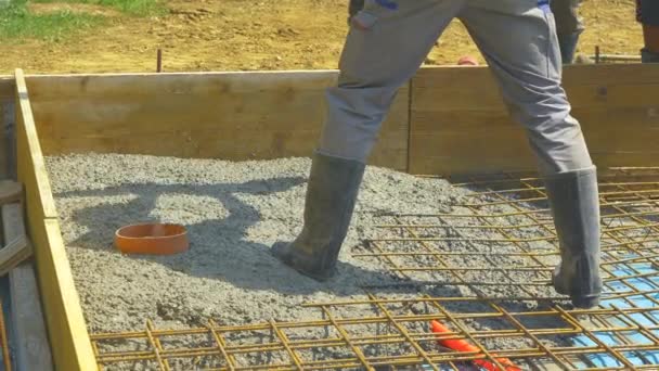 CLOSE UP: Aannemers gieten ruw nat beton over een versterkt stalen net. — Stockvideo