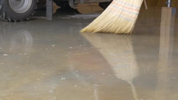LOW ANGLE: Broom with straw bristles sweeps away dirty water covering floor. — Vídeo de Stock