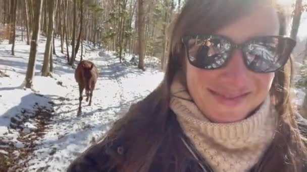 SELFIE: Young woman walks horses down empty forest trail on beautiful winter day — Stock Video