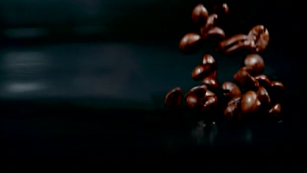 MACRO: Primer plano de granos de café moca cayendo y rebotando alrededor de la mesa — Vídeo de stock