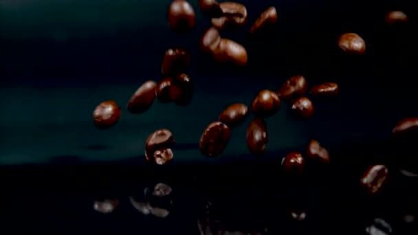 MACRO: Fragrant roasted coffee beans scatter across the glossy black counter. — Stockvideo