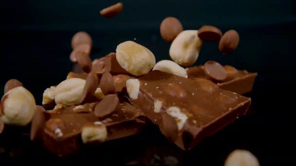 MACRO: Nüsse und Schokoladenchips verteilen sich auf ein paar Quadrate milchiger Schokolade. — Stockvideo