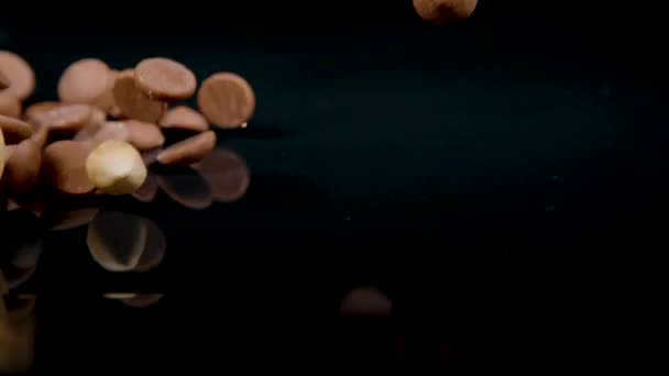 MACRO: Een mix van gerolde haver, geblancheerde hazelnoten en chocolade druppels vallen. — Stockvideo