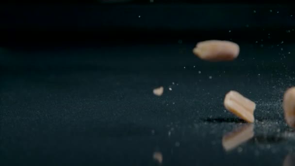 MACRO: Organically grown salty peanuts fall onto the shiny kitchen countertop. — Stockvideo