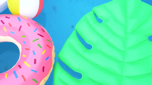 TOP DOWN: Dešťové kapky padají na barevné hračky vznášející se kolem prázdného bazénu. — Stock video