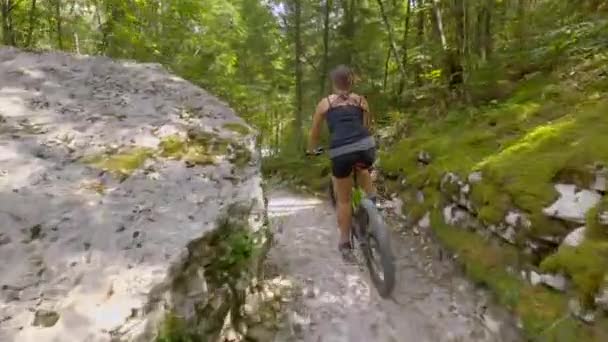 Jonge vrouwelijke toerist fietst op een elektrische fiets langs een schilderachtig bospad in Bovec — Stockvideo