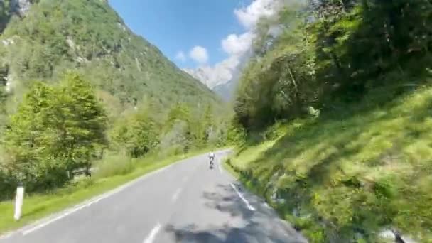 Jovem turista monta uma bicicleta elétrica ao longo de uma estrada cênica no vale do Soca. — Vídeo de Stock