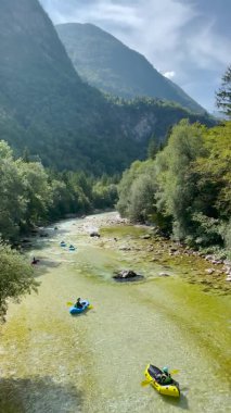 Turistler güneşli bir günde tembel Soca nehrinde kanolarını yüzdürürler..