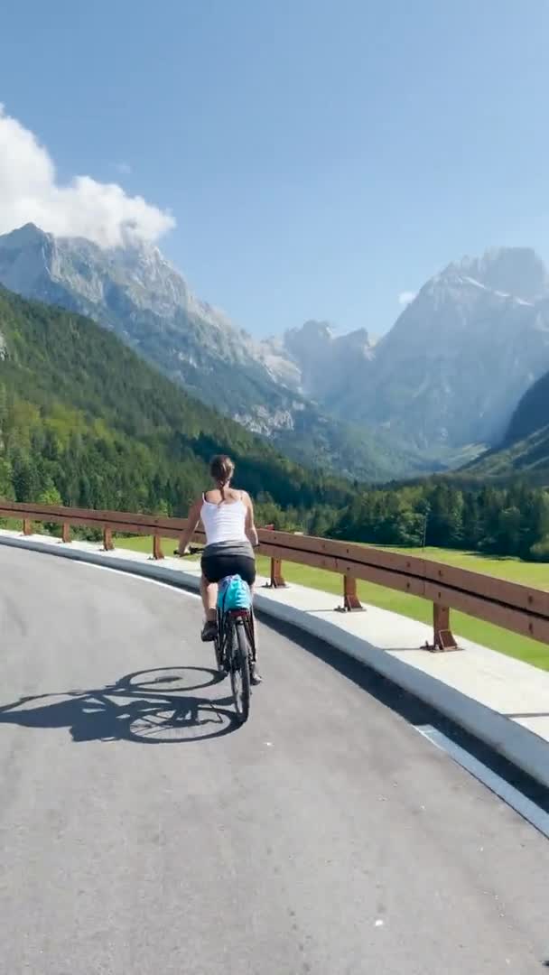 VERTICAL: Žena jezdí na elektrickém kole po malebné horské silnici ve Slovinsku. — Stock video