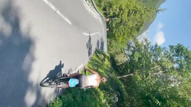 VERTICAL: Kvinna rider en elektrisk cykel längs en naturskön väg i Bovec, Slovenien. — Stockvideo