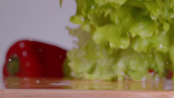 MACRO: ใบผักกาดเปียกและมะเขือเทศเชอร์รี่ตกลงบนกระดานตัด . — วีดีโอสต็อก