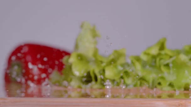 MACRO: Umyte pomidory i sałata lodowa uderzyły w blat kuchni drzewnej. — Wideo stockowe