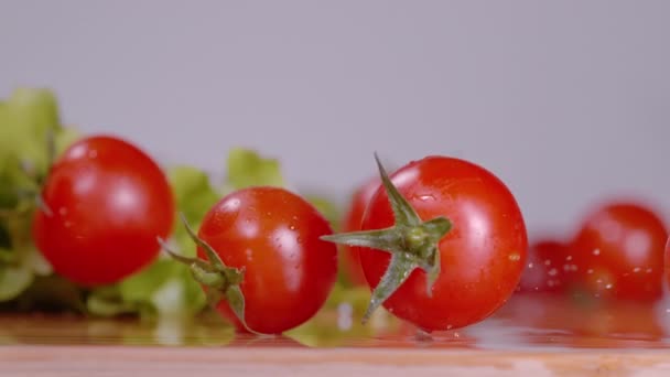 MACRO: Tomates cherry rodar alrededor de la tabla de cortar húmedo mientras se hace una ensalada. — Vídeo de stock