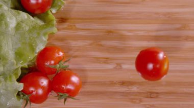 Kiraz domateslerinin ıslak doğrama tahtasına düşüşünün detaylı görüntüsü.