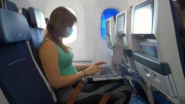 CLOSE UP: Young female traveller works on her laptop during a long flight. — Stock Video
