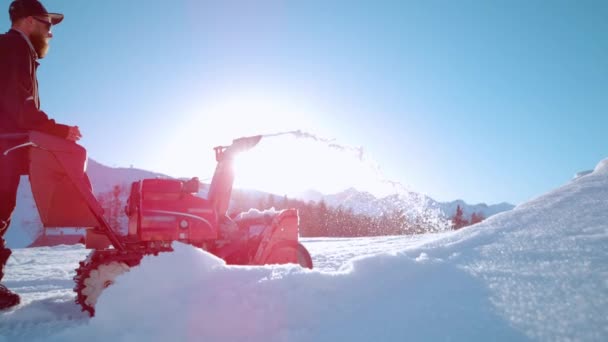COPY SPACE, LENS FLARE: Brodaty człowiek pracuje dmuchawy śniegu w słoneczny zimowy dzień — Wideo stockowe