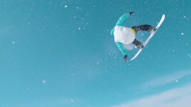 FLARE DE LA LENTE: Snowboarder hace un truco de agarre giratorio mientras monta en un snowpark. — Vídeos de Stock