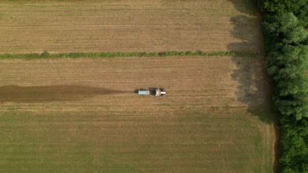 TOP DOWN: Volare sopra un trattore fertilizzando un campo coltivato vicino ad un vigneto. — Video Stock