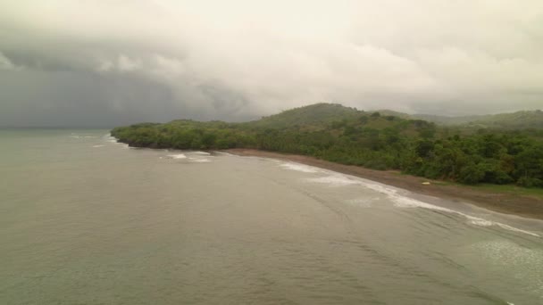 AERIAL: Nuvens de trovoada escuras rolando sobre a exótica praia de areia e floresta tropical — Vídeo de Stock