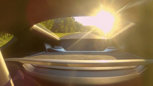 FERMER : Rayons de soleil dorés brillent à travers la vitre arrière de la voiture conduisant sur l'autoroute. — Video