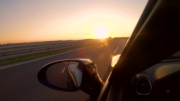CLOSE UP Літні вечірні сонячні промені світяться на спортивному автомобілі, що їде порожньою автострадою — стокове відео