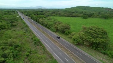 Meşhur Pan-Amerikan karayolunu çevreleyen yemyeşil doğanın üzerinde uçuyorlar. Panamericana boyunca giden araba ve kamyonların manzaralı insansız hava aracı bakış açısı. Çevredeki otoban yağmur ormanları.